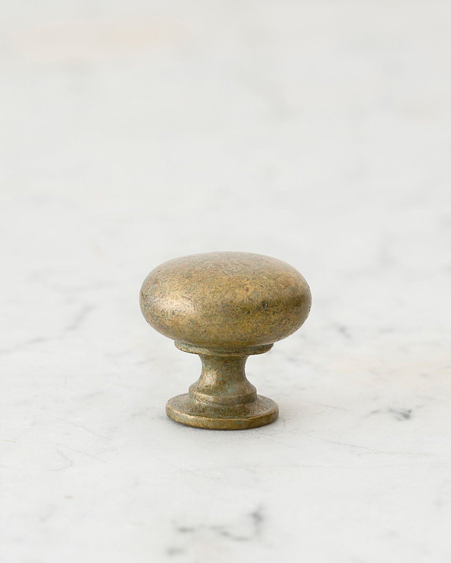 A 'Small' classic knob for a kitchen cupboard or drawer with an aged verdigris brass finish and unique dented textures as if was made by an artisan blacksmith centuries ago.