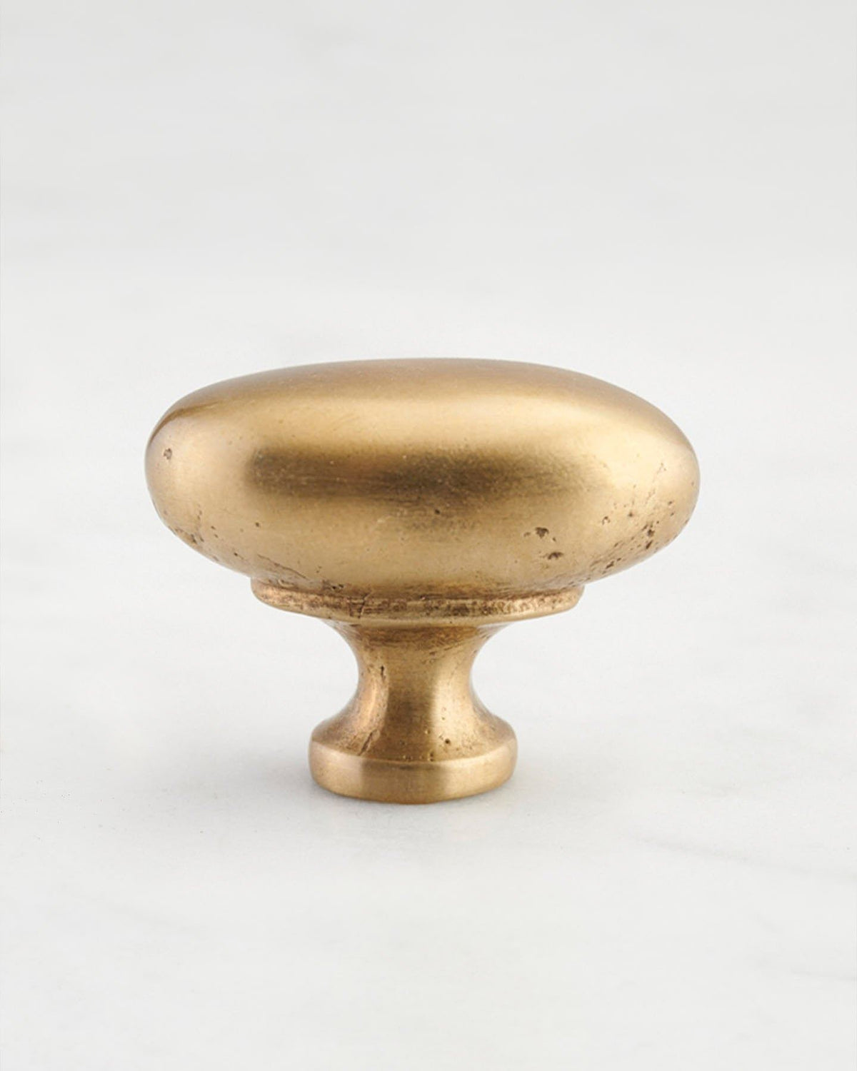 A 'Large' oval-shaped knob for a kitchen cupboard or drawer with an aged brass finish and unique dented textures that makes it look like a beloved, well aged brass from centuries ago. TEST