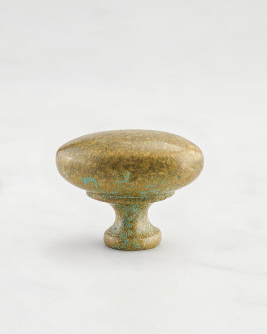 A 'Medium' oval-shaped knob for a kitchen cupboard or drawer with an aged verdigris brass finish and unique dented textures as if was made by an artisan blacksmith centuries ago.