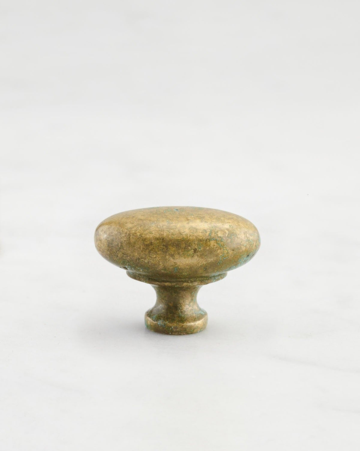 A 'Small' oval-shaped knob for a kitchen cupboard or drawer with an aged verdigris brass finish and unique dented textures as if was made by an artisan blacksmith centuries ago. TEST