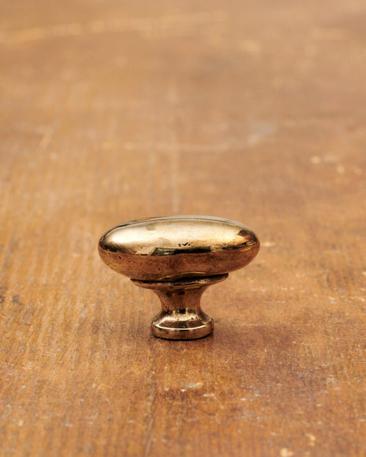 A 'Small' oval-shaped knob for a kitchen cupboard or drawer with a warm burnished brass finish and unique dented textures as if was made by an artisan blacksmith centuries ago.