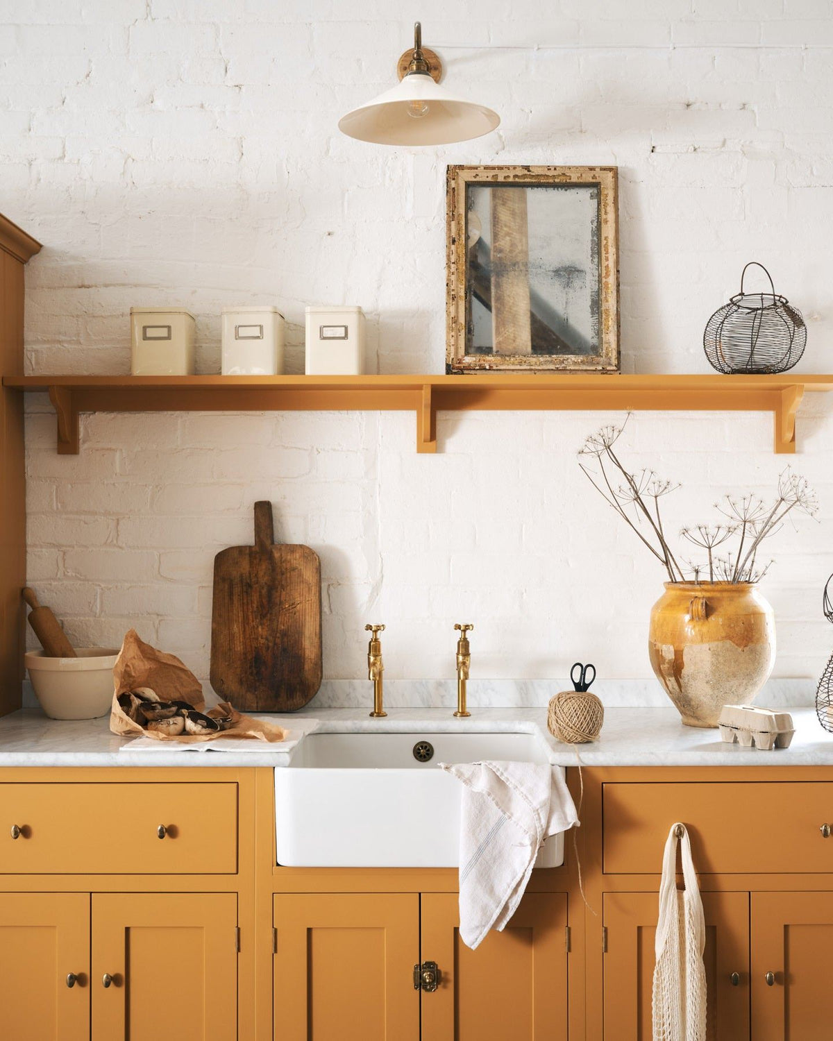 A straight-on view of a yellow painted Shaker-style kitchen sink cupboard with small oval-shaped knobs in a warm burnished brass finish.| Small shown TEST