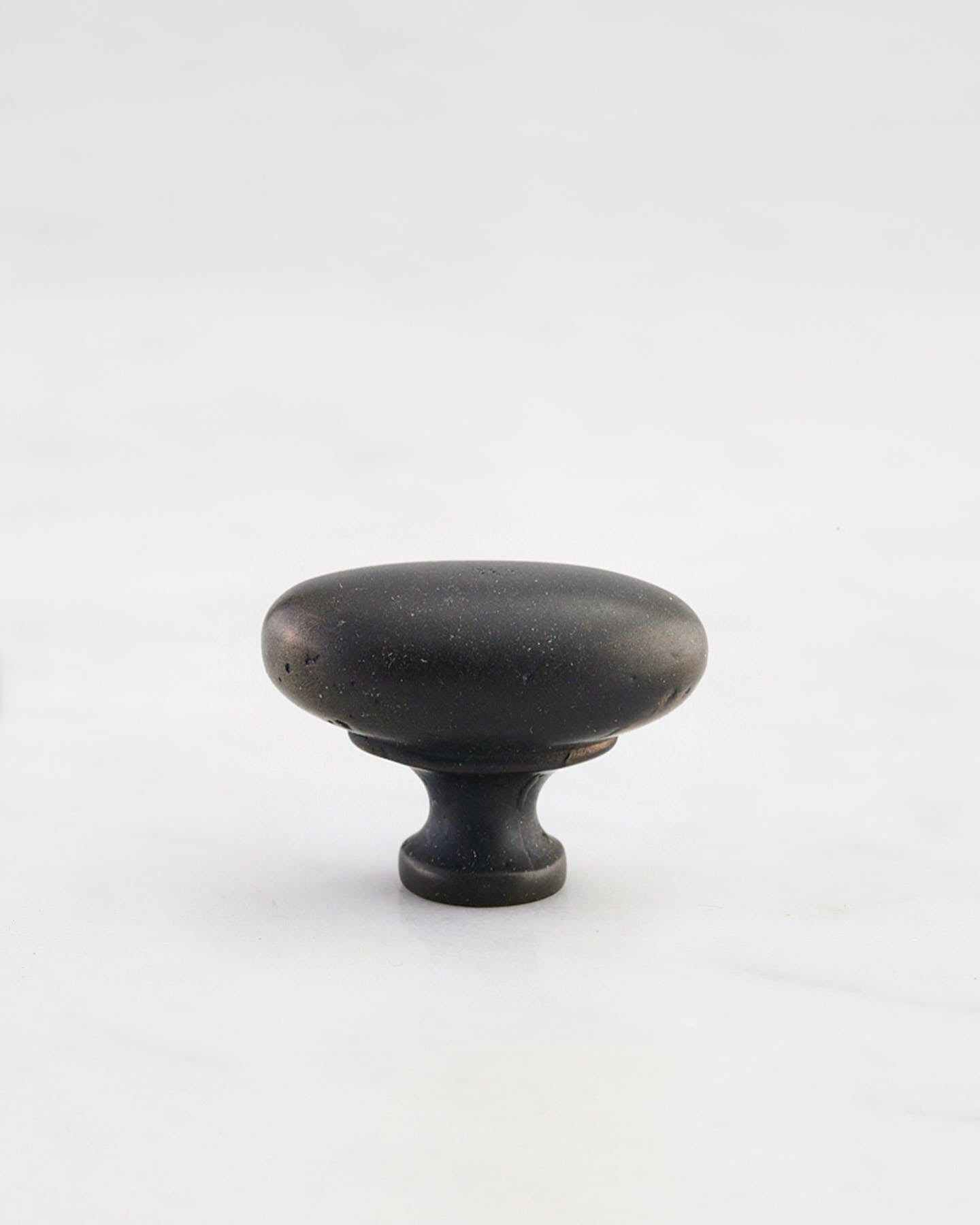 A 'Small' oval-shaped knob for a kitchen cupboard or drawer with a matt black bronze finish that makes it look like a beloved, well aged brass from centuries ago.