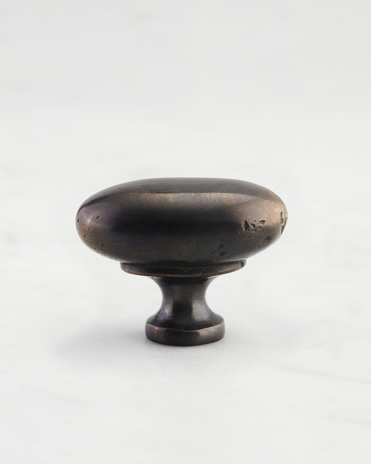 A 'Medium' oval-shaped knob for a kitchen cupboard or drawer with a dark oxidised bronze finish and unique dented textures as if was made by an artisan blacksmith centuries ago. TEST