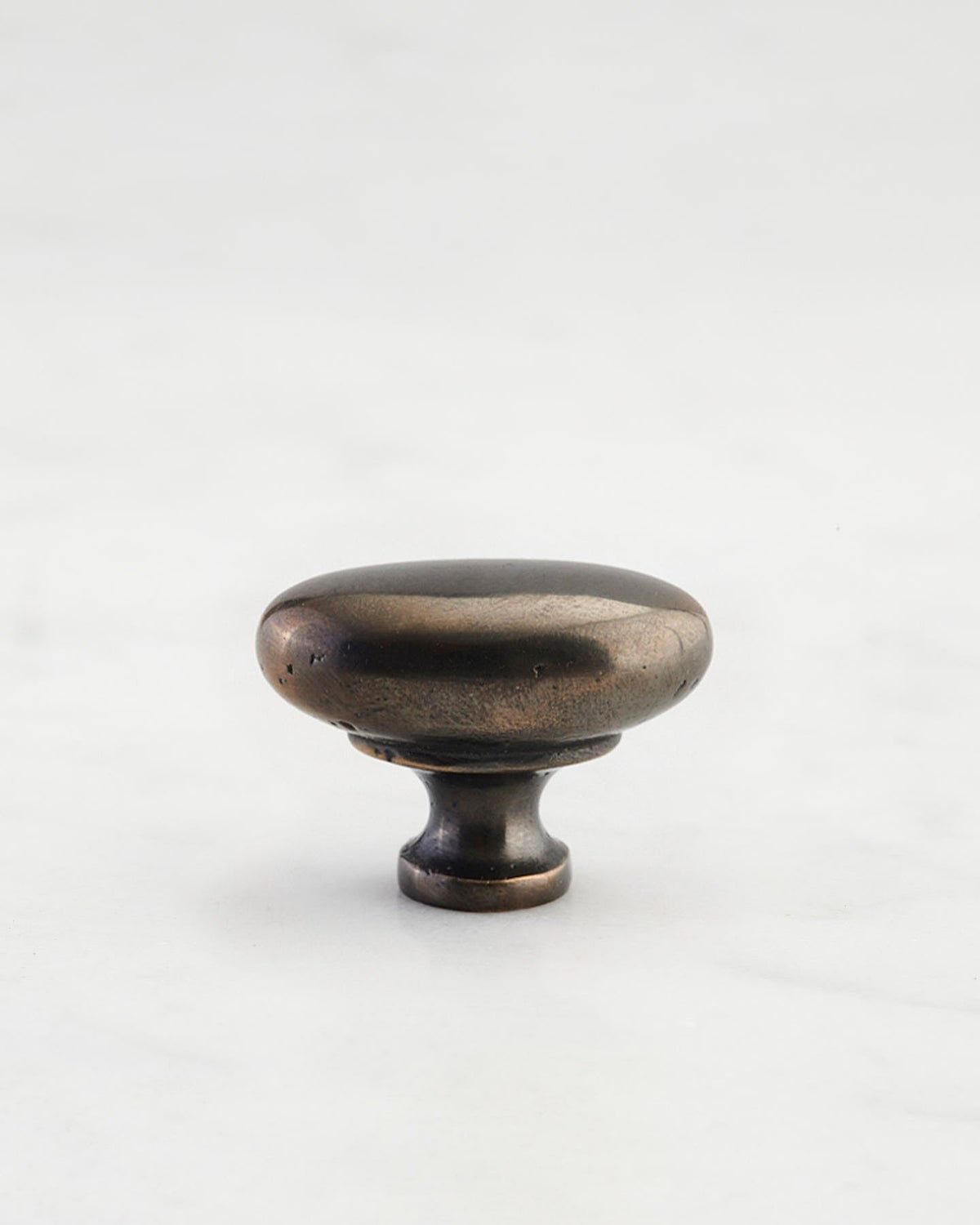 A 'Small' oval-shaped knob for a kitchen cupboard or drawer with a dark oxidised bronze finish and unique dented textures as if was made by an artisan blacksmith centuries ago. TEST