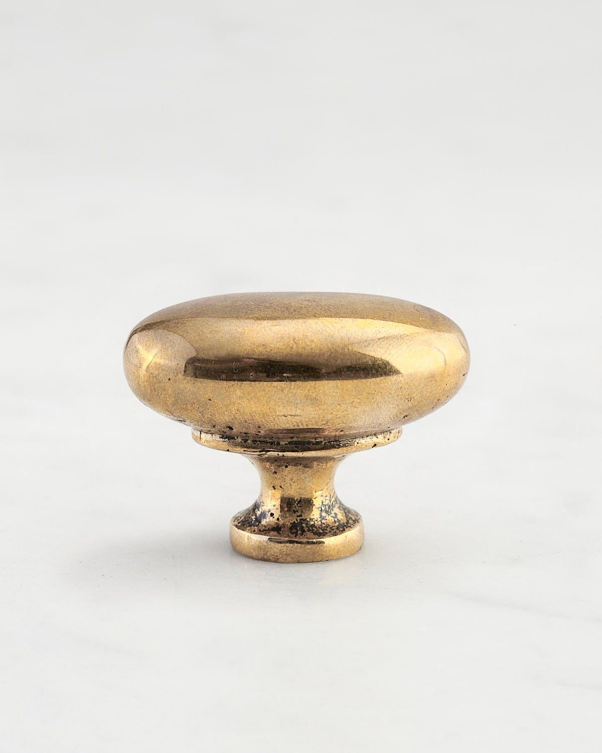 A 'Medium' oval-shaped knob for a kitchen cupboard or drawer with a bright polished bronze finish and unique dented textures that makes it look like a beloved, well aged bronze from centuries ago. TEST