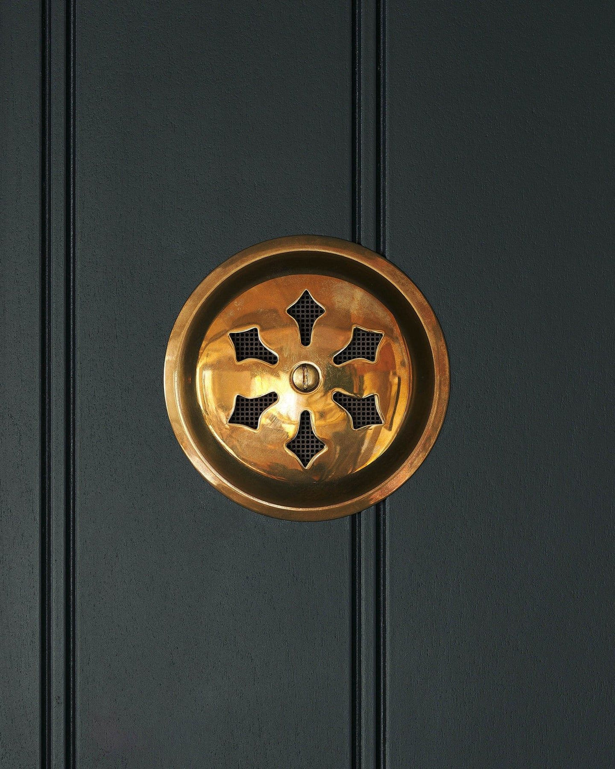 A Victorian-inspired circular brass ventilation grille with traditional decorative cutouts. TEST