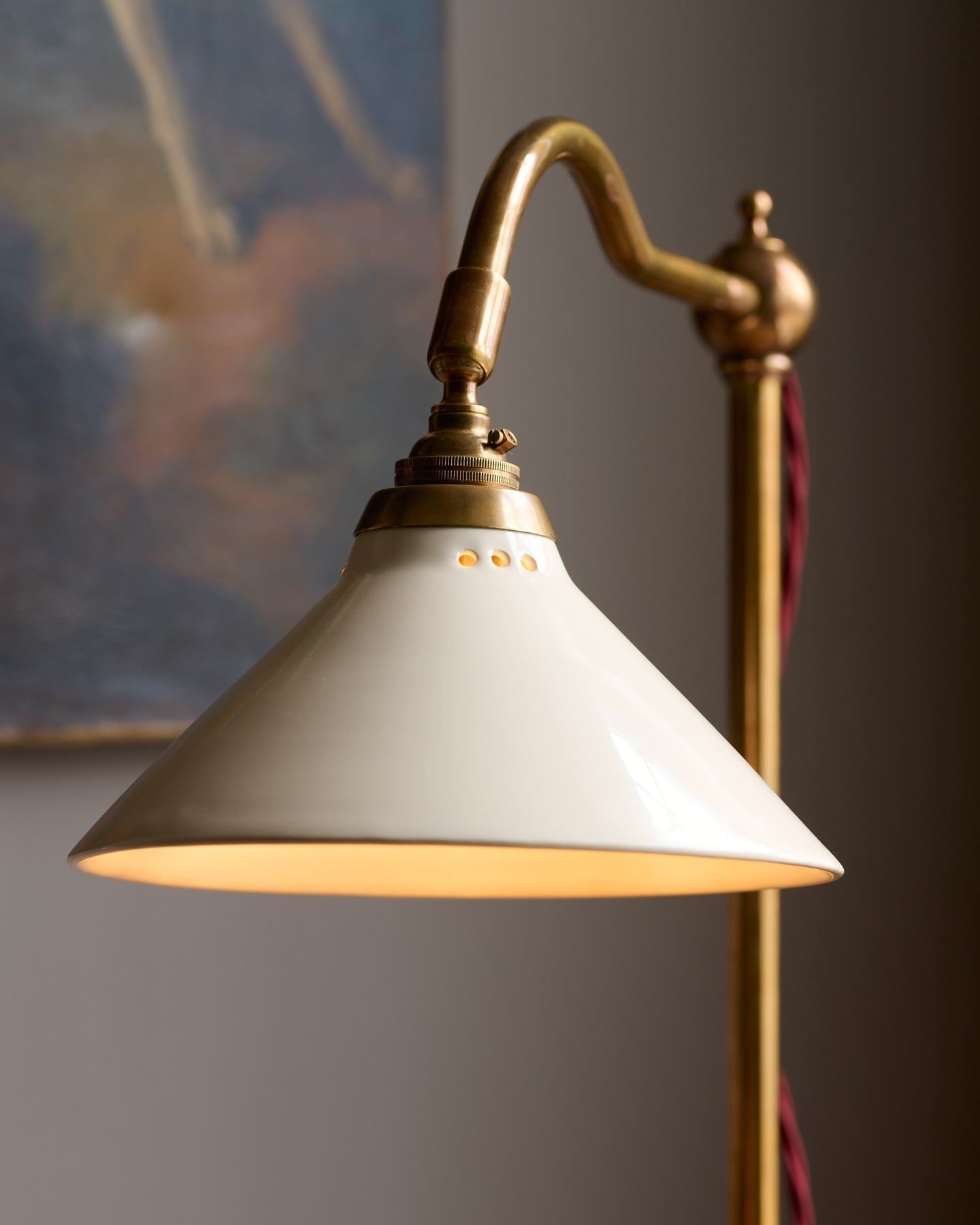 A close-up view of a pointed brass finial with red twisted fabric flex cord leading into the back.