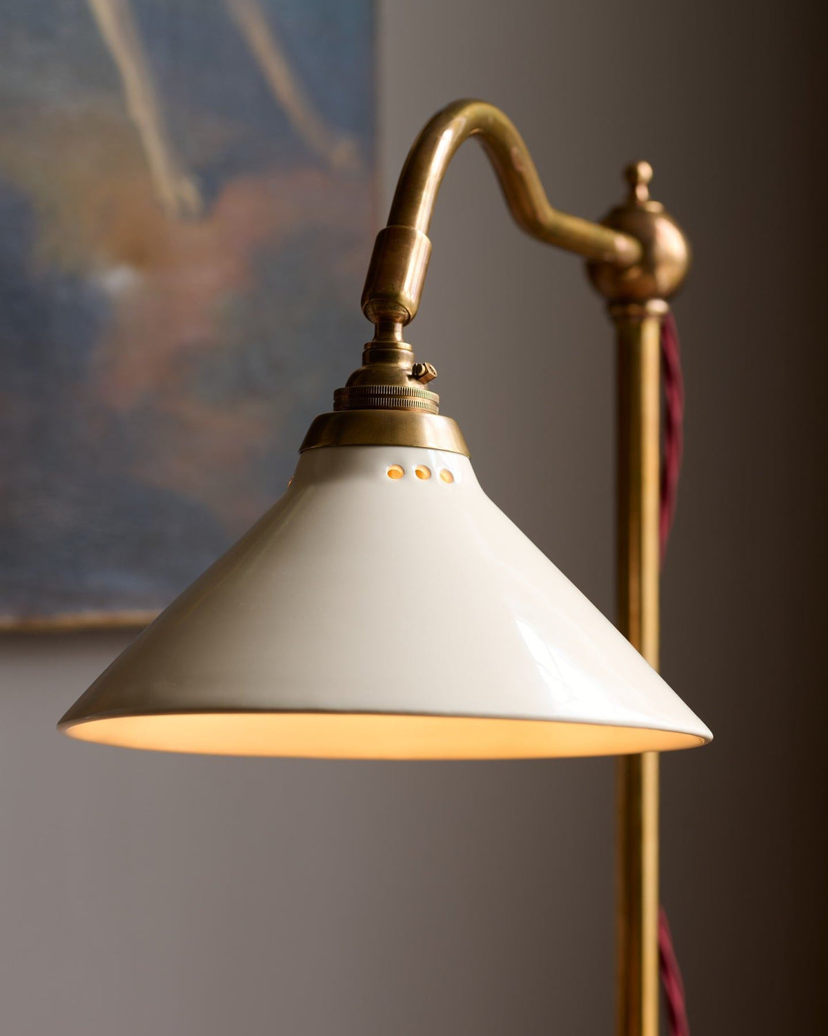A close-up view of a pointed brass finial with red twisted fabric flex cord leading into the back. TEST