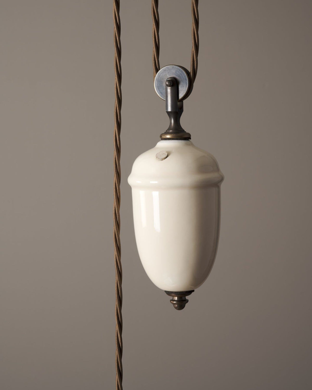 A close-up view of a cream glazed ceramic counterweight for a rise and fall light. TEST