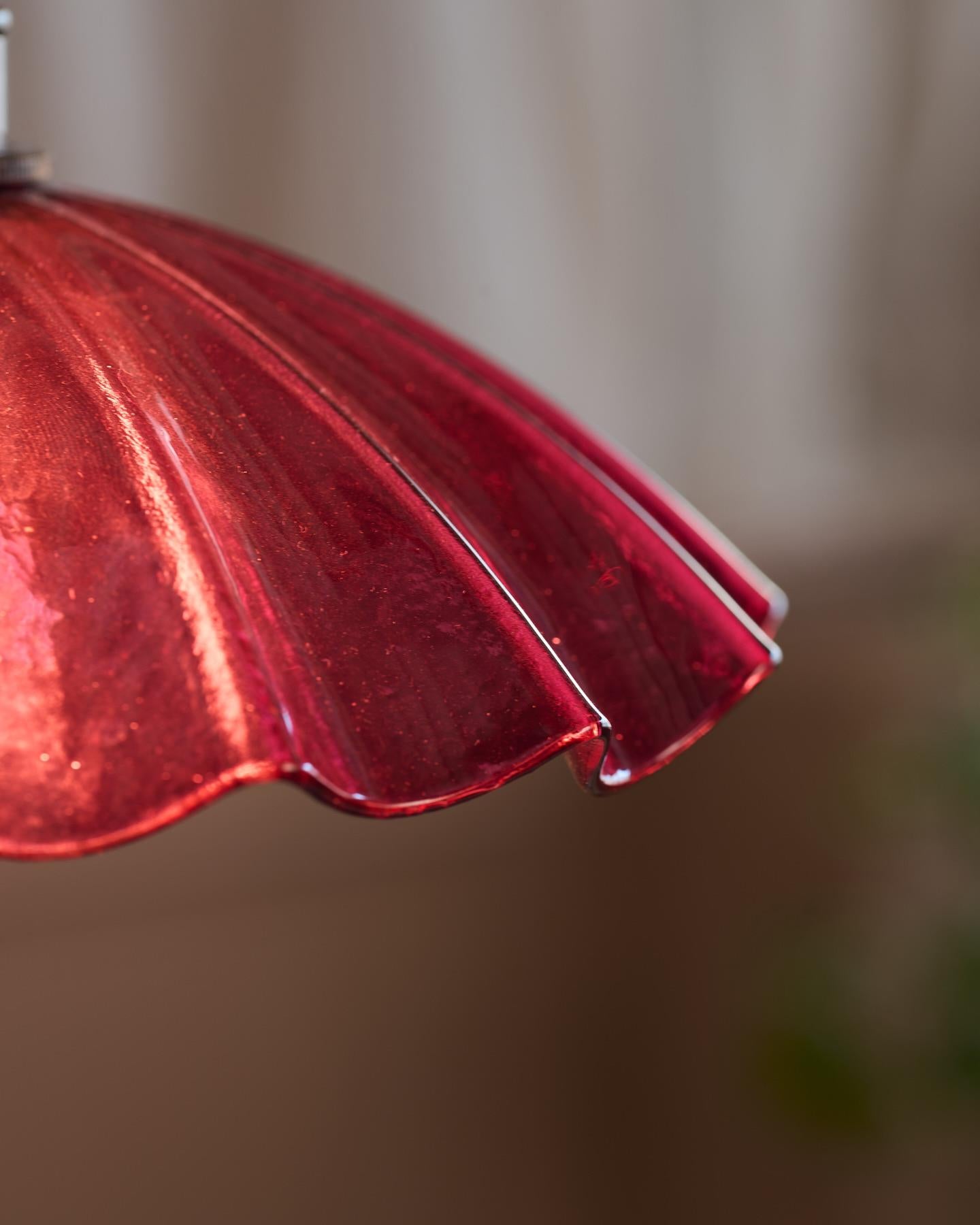 A close-up view of a small frilly cranberry glass light shade.