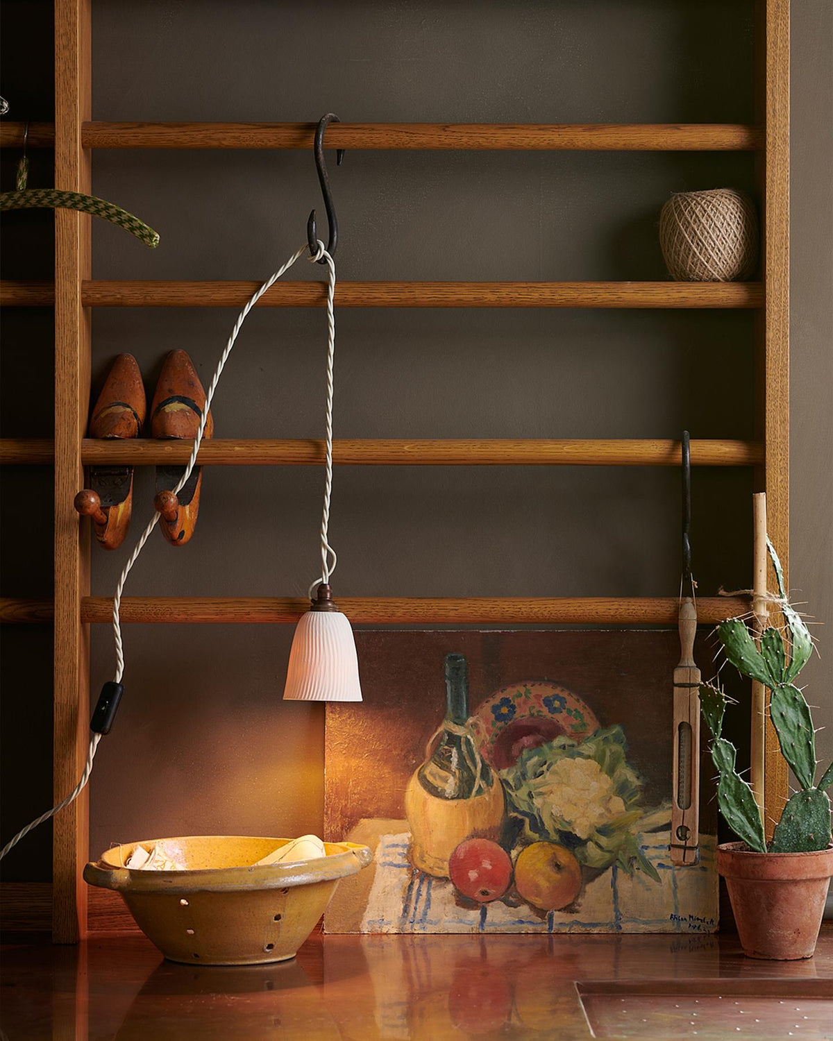 A Mediterranean-style kitchen with white painted cabinetry, white walls, terracotta flooring and an assortment of unglazed porcelain pendant lights hanging at various heights. TEST