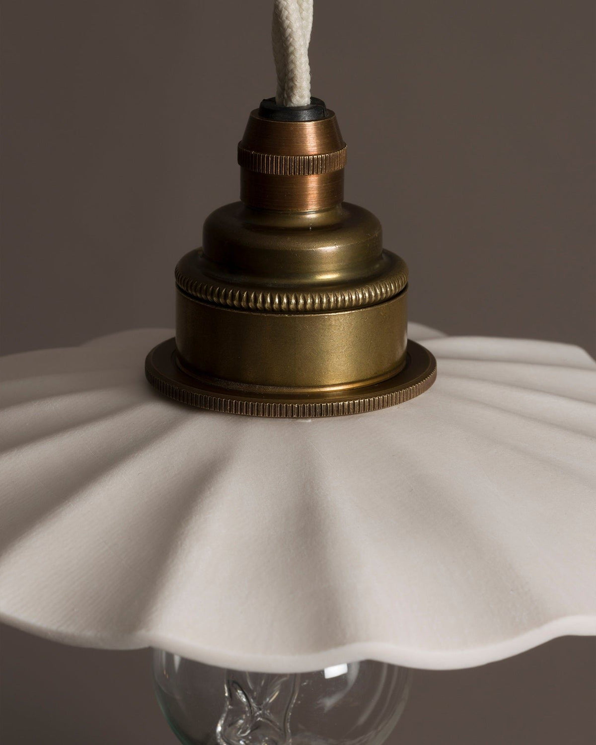 A close-up view of an unglazed porcelain pendant light with wide pleats. TEST