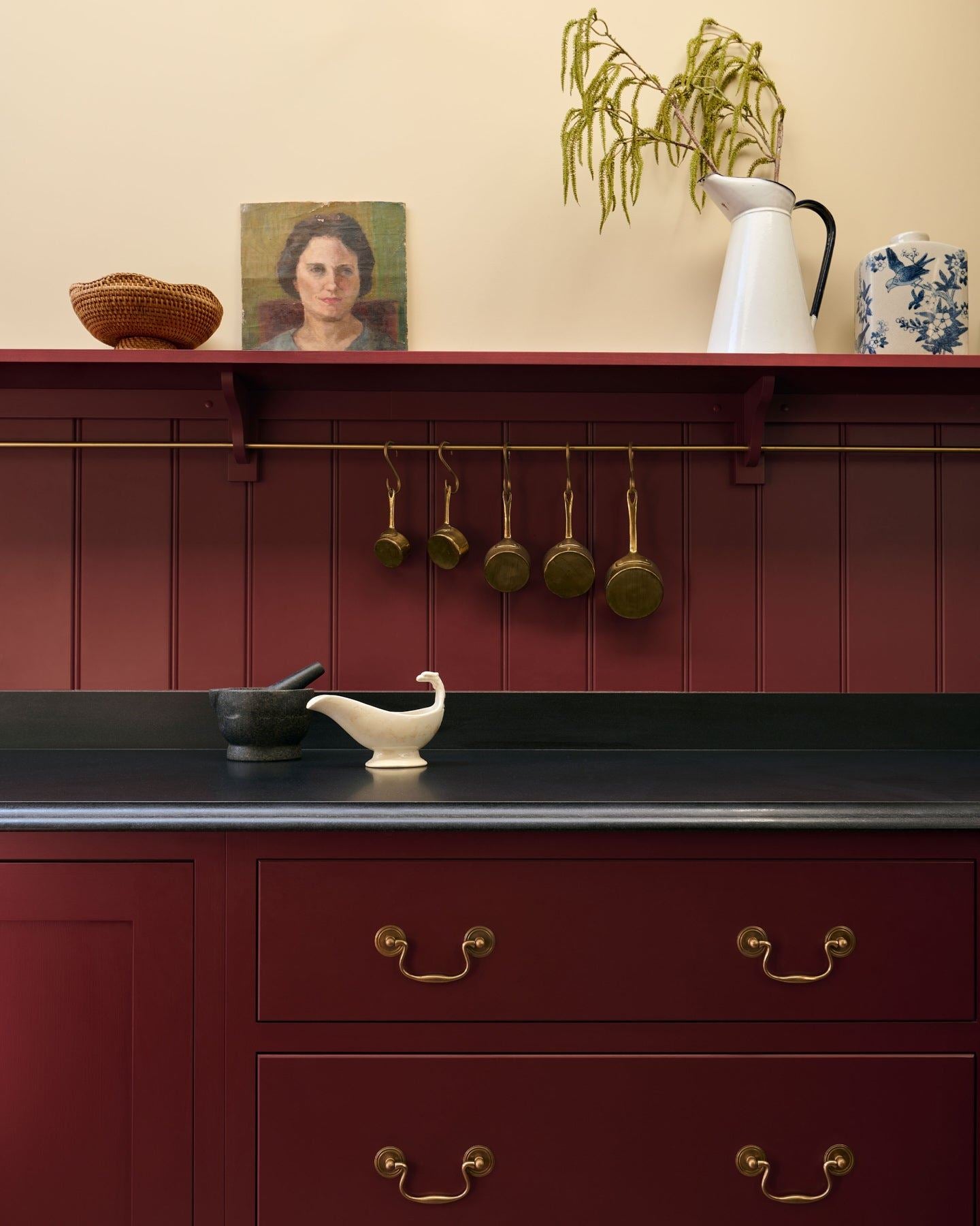 A close-up view of red painted Shaker-style kitchen drawers with a black granite worktop and red tongue and groove panelling above.