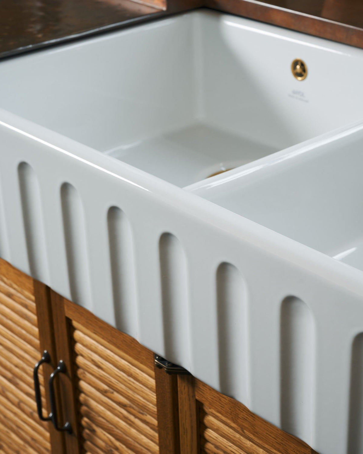 A close-up oblique view of the fluted front of an extra large double bowl ceramic Belfast sink. TEST