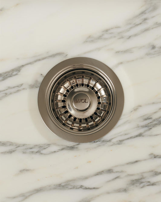An overhead view of a basket waste strainer in a polished chrome finish, there is a small 'deVOL' logo in the middle of the central finial.