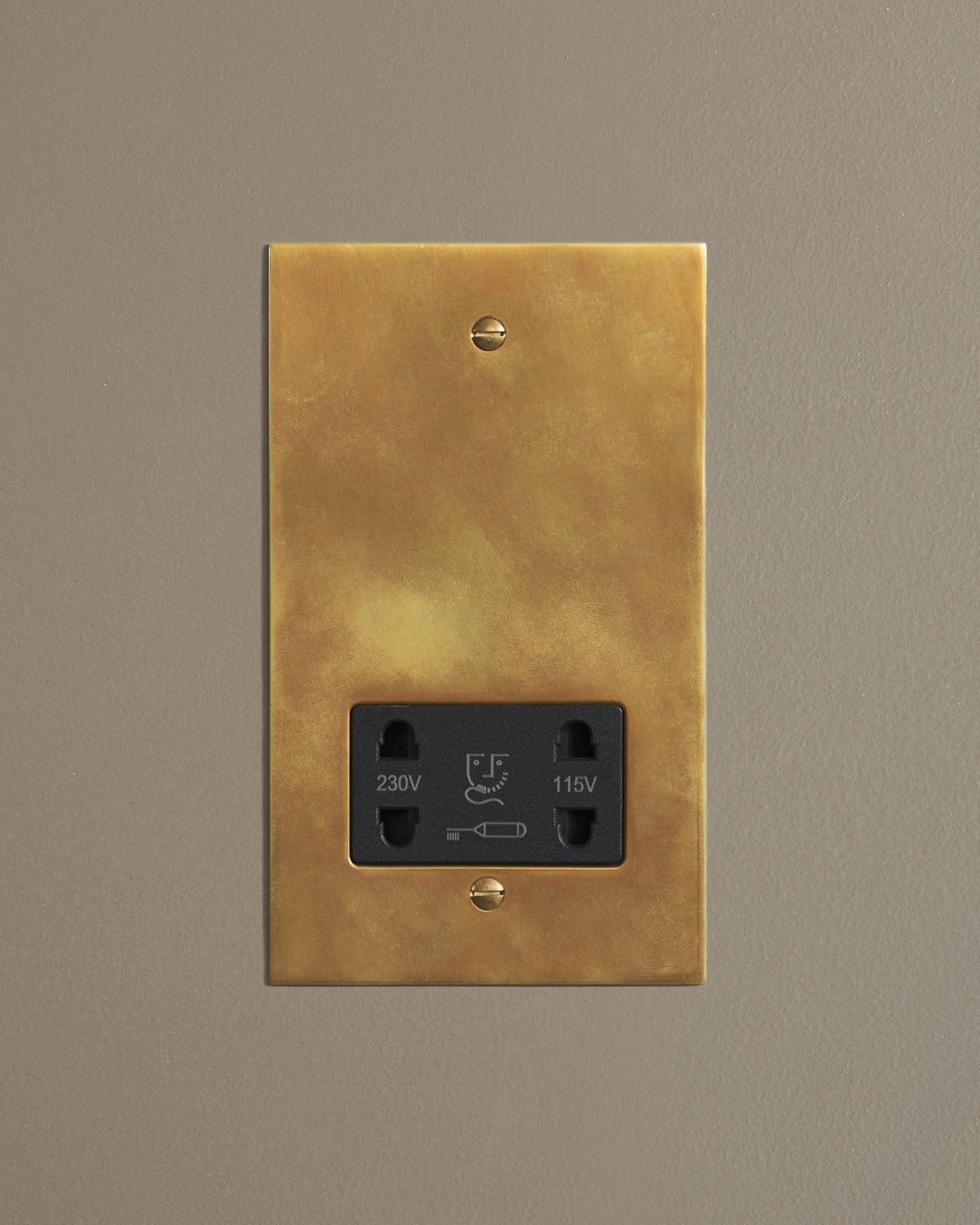 A straight-on view of a classic twin shaver socket in a warm burnished brass finish.