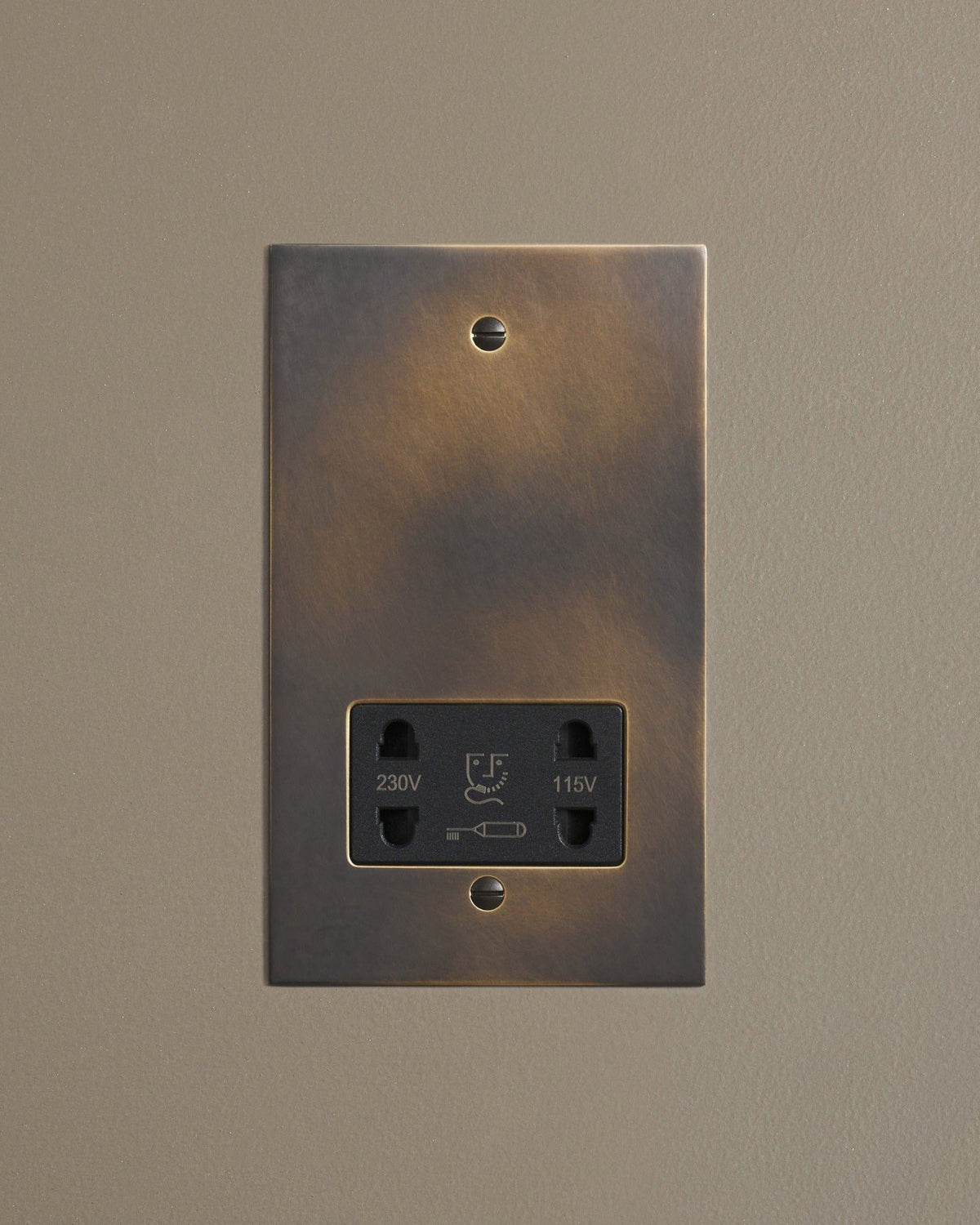 A straight-on view of a classic twin shaver socket in a dark oxidised brass finish. TEST