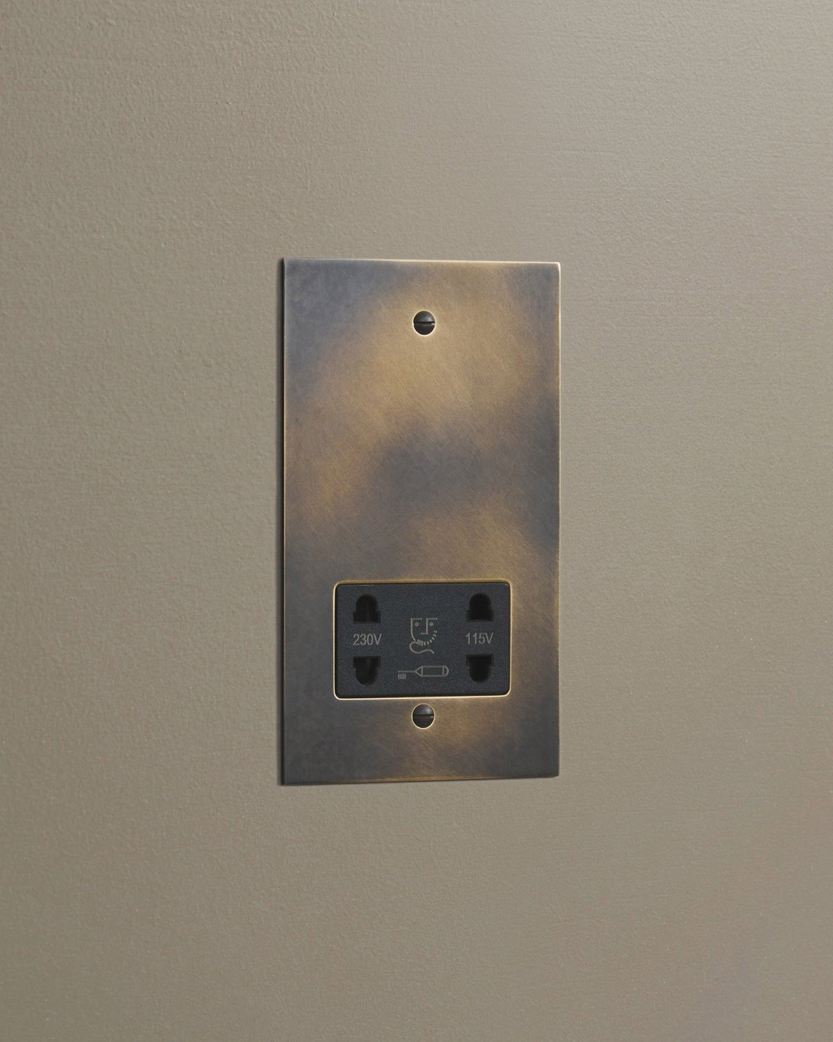 An oblique view of a classic twin shaver socket in a dark oxidised brass finish. TEST