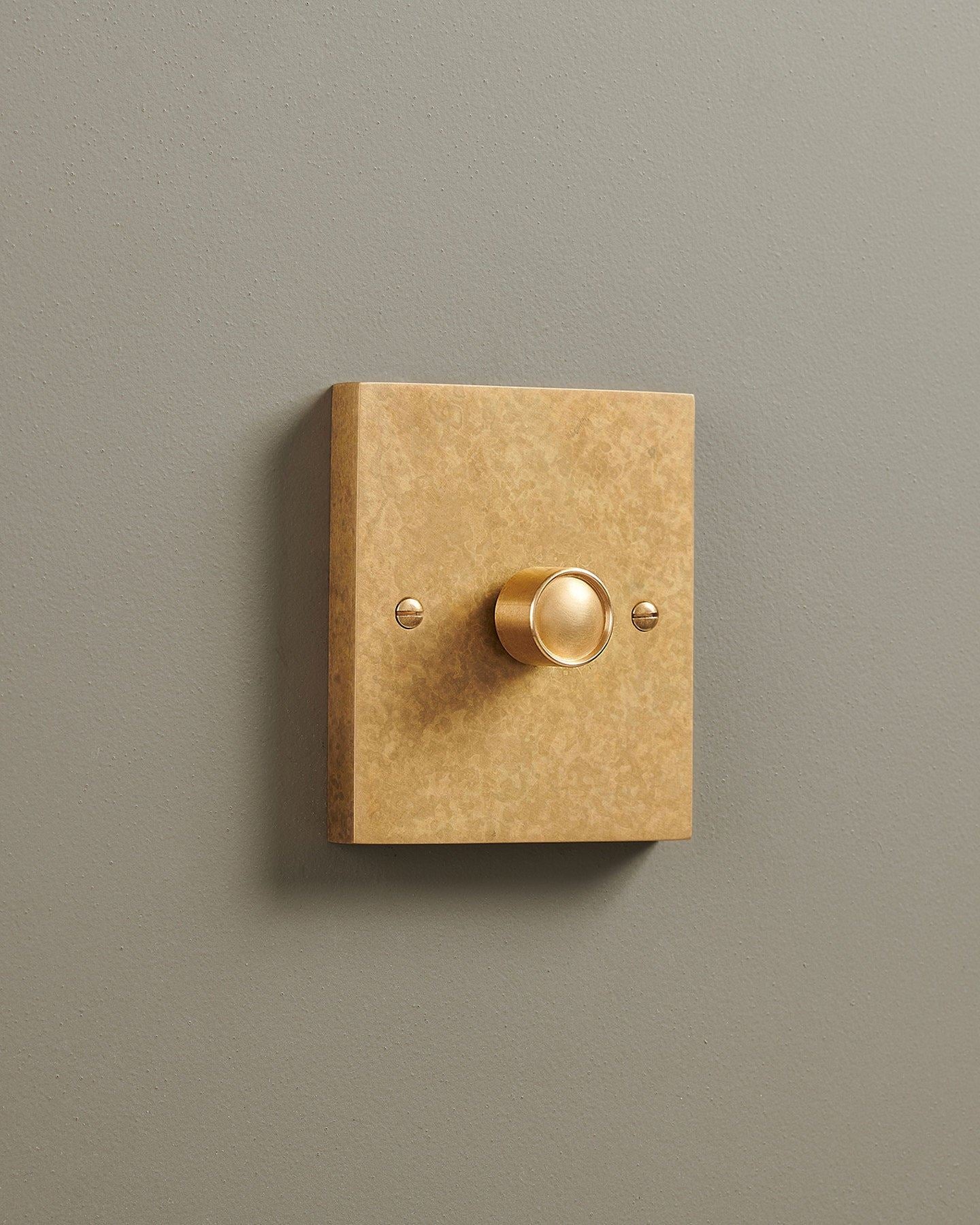 An oblique view of a 1 gang box dimmer switch in a mottled aged brass finish.