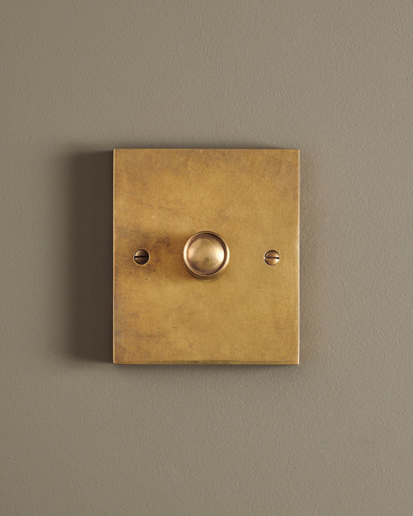 A straight-on view of a 1 gang box dimmer switch in a warm burnished brass finish.