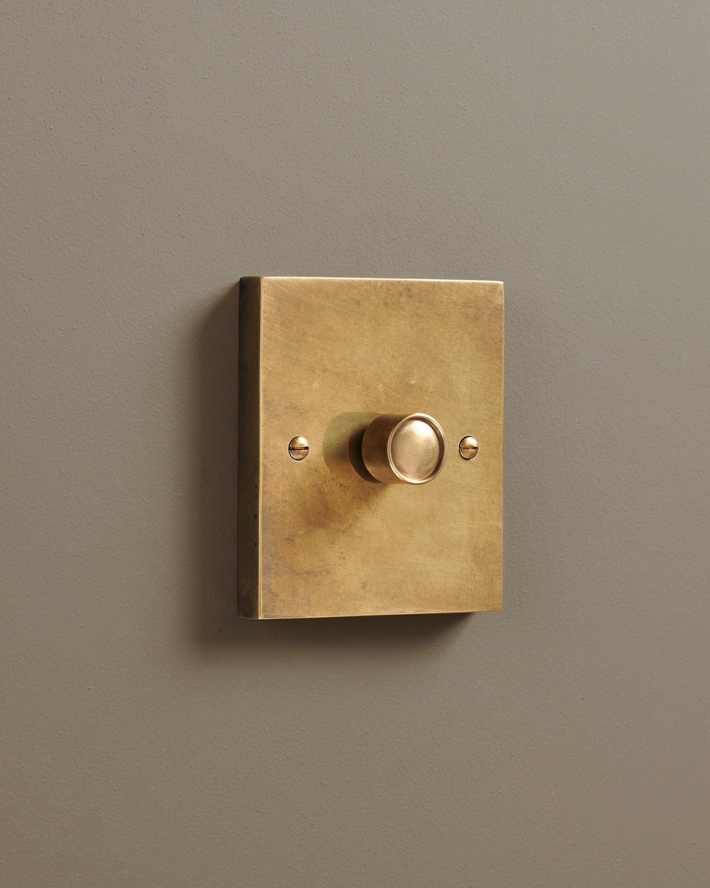 An oblique view of a 1 gang box dimmer switch in a warm burnished brass finish.