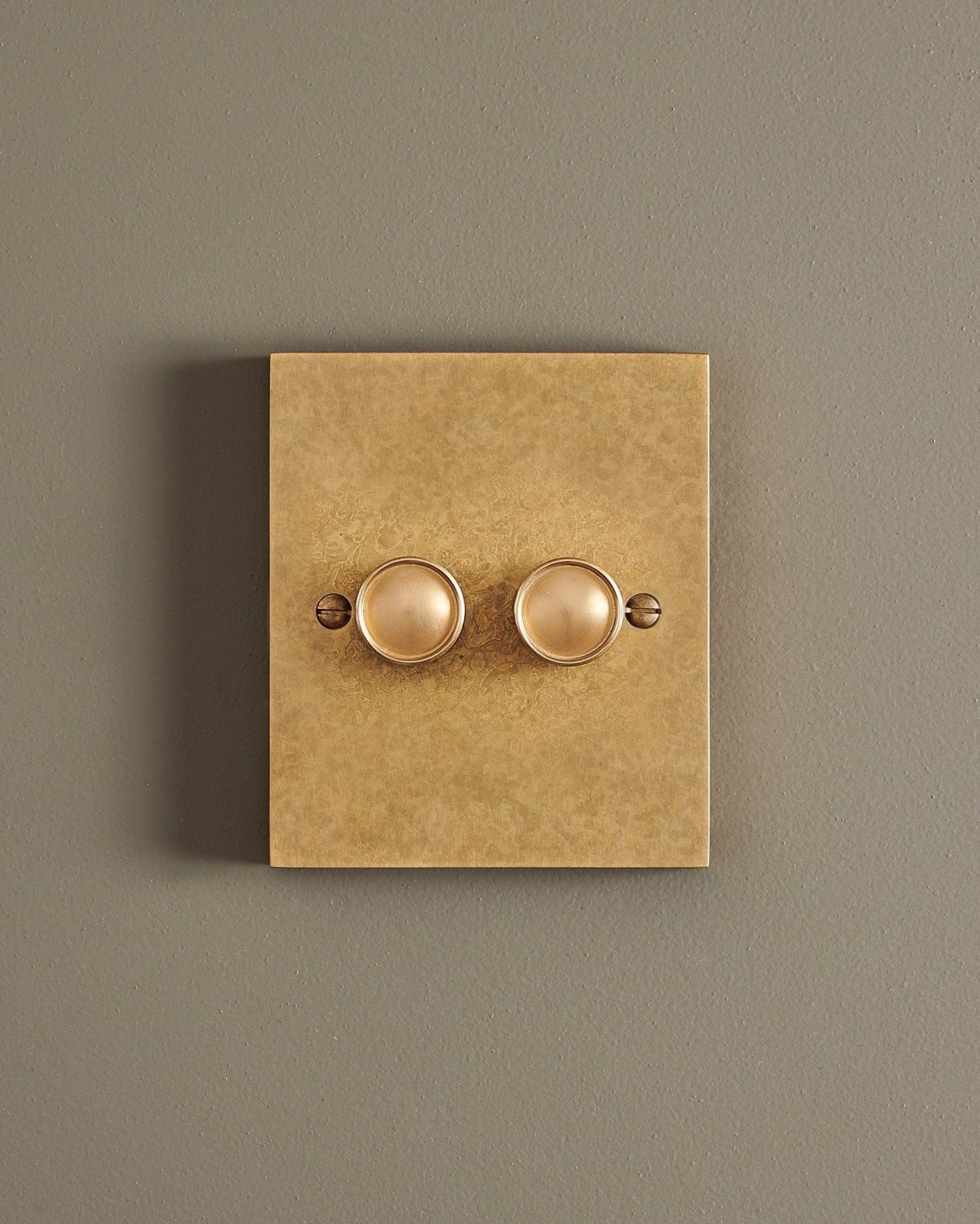 A straight-on view of a 2 gang box dimmer switch in a mottled aged brass finish.