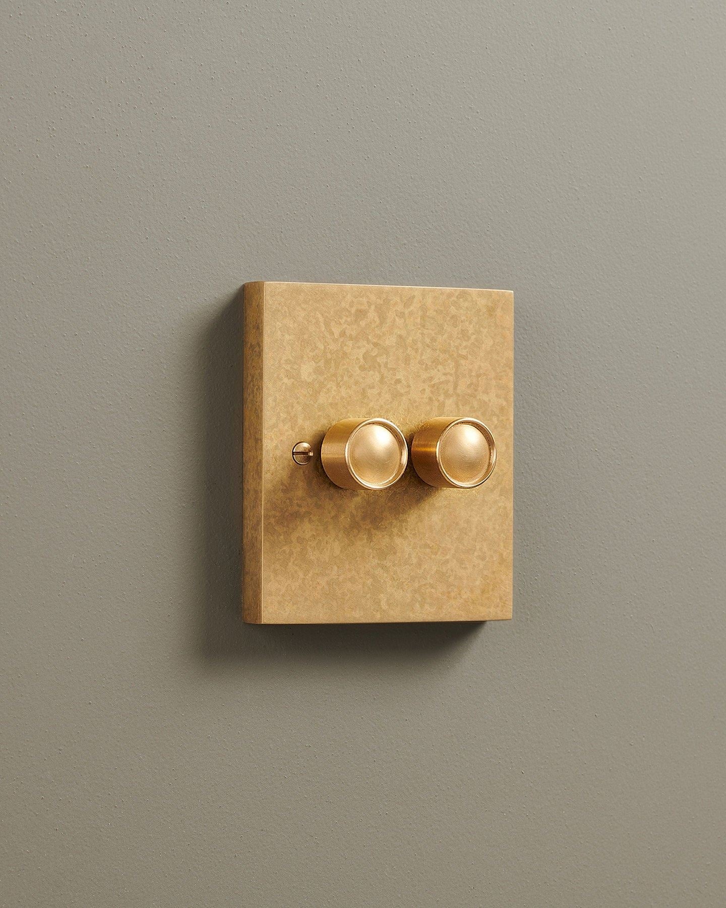 An oblique view of a 2 gang box dimmer switch in a mottled aged brass finish.