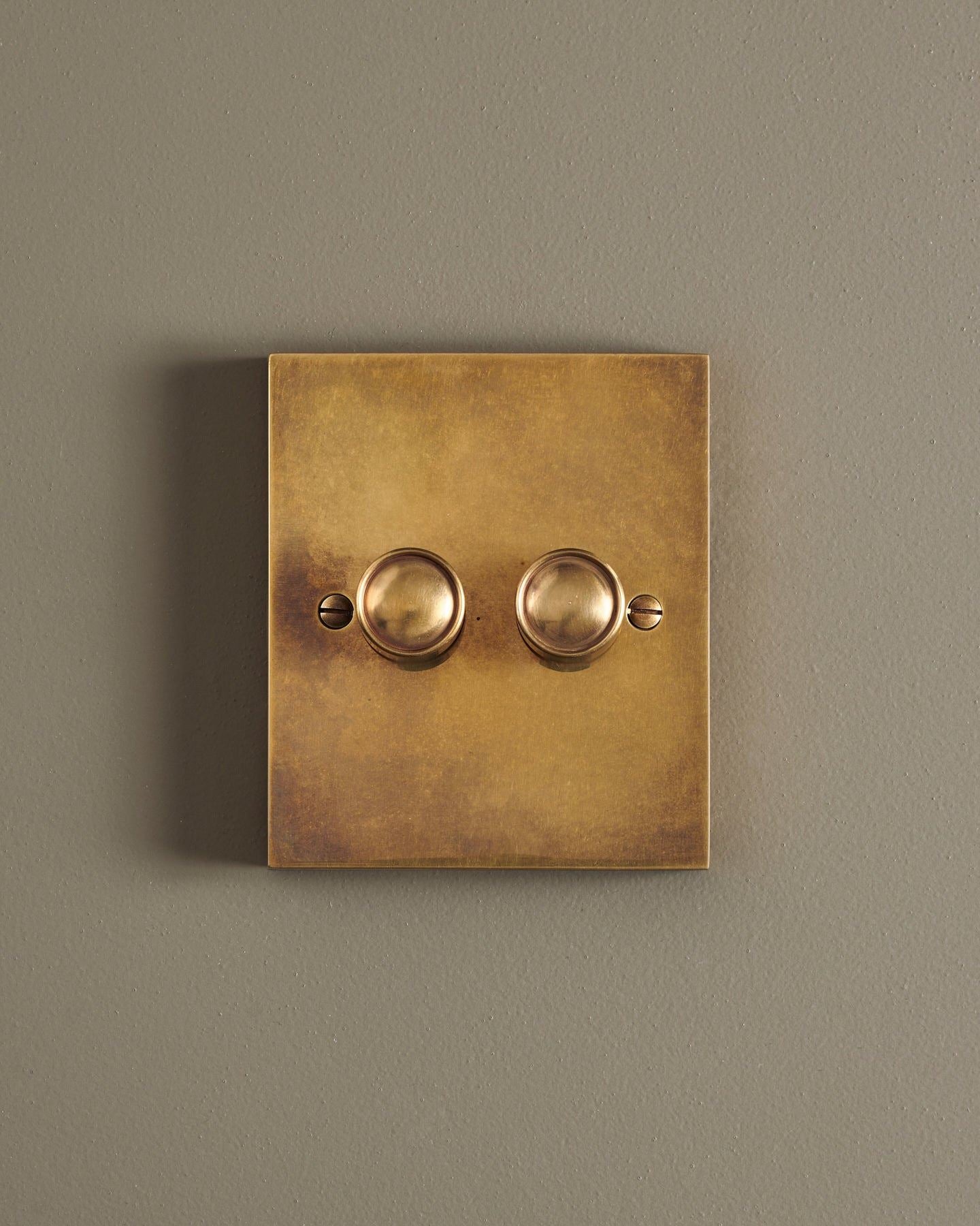 A straight-on view of a 2 gang box dimmer switch in a warm burnished brass finish.