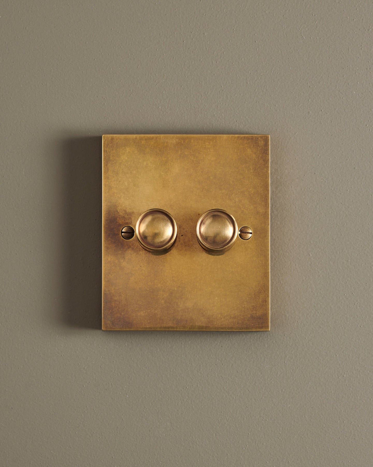 A straight-on view of a 2 gang box dimmer switch in a warm burnished brass finish. TEST