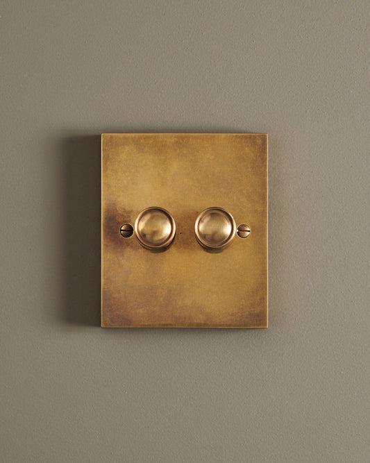 A straight-on view of a 2 gang box dimmer switch in a warm burnished brass finish.