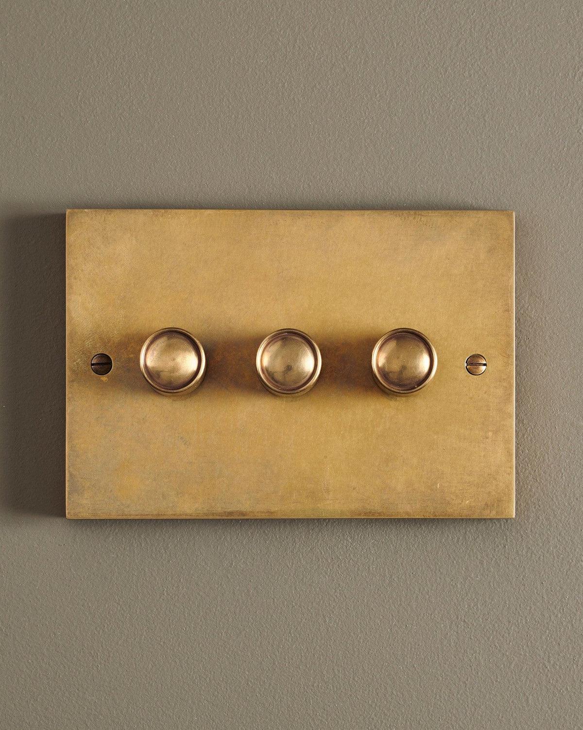A straight-on view of a 3 gang box dimmer switch in a warm burnished brass finish. TEST