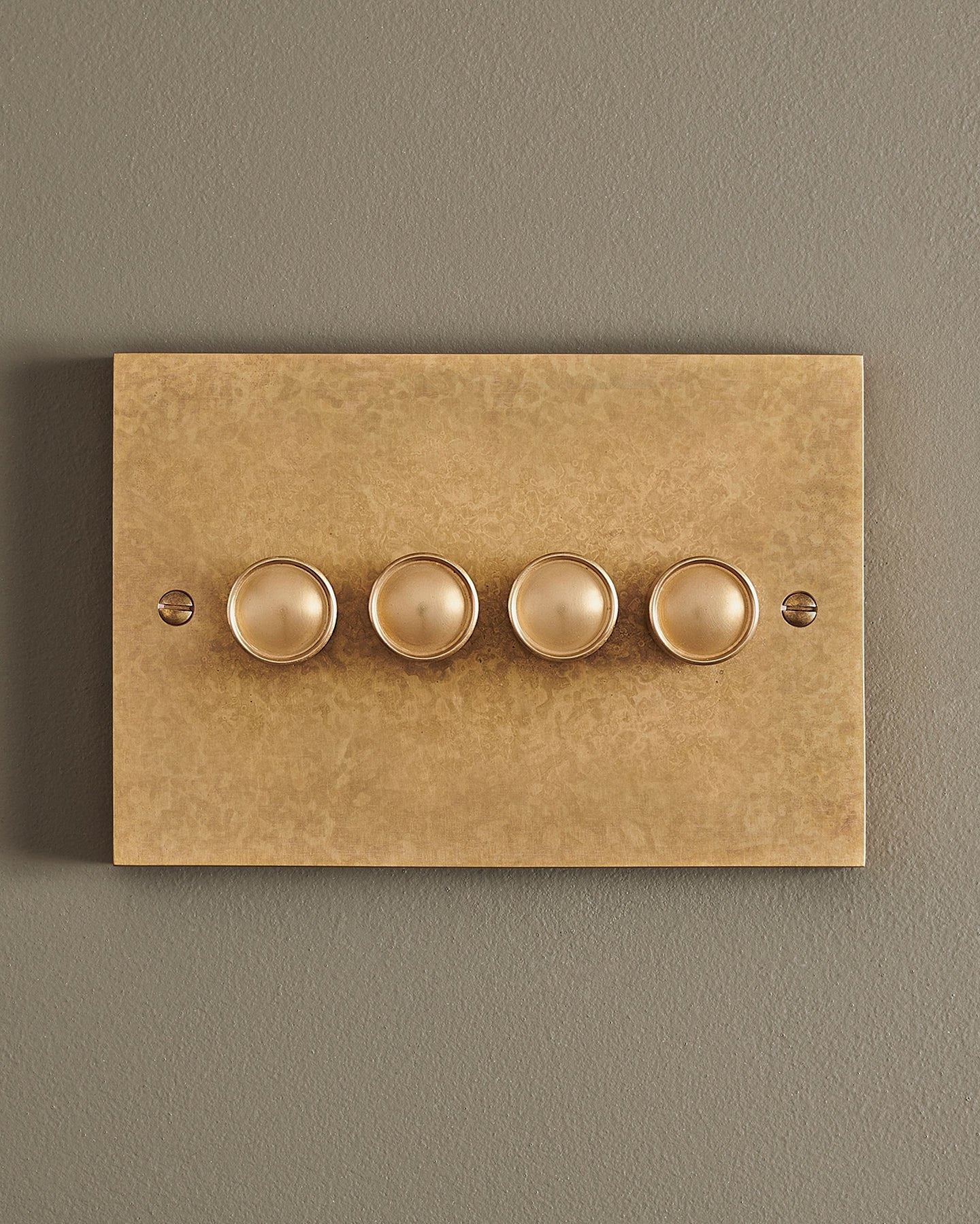 A straight-on view of a 4 gang box dimmer switch in a mottled aged brass finish.