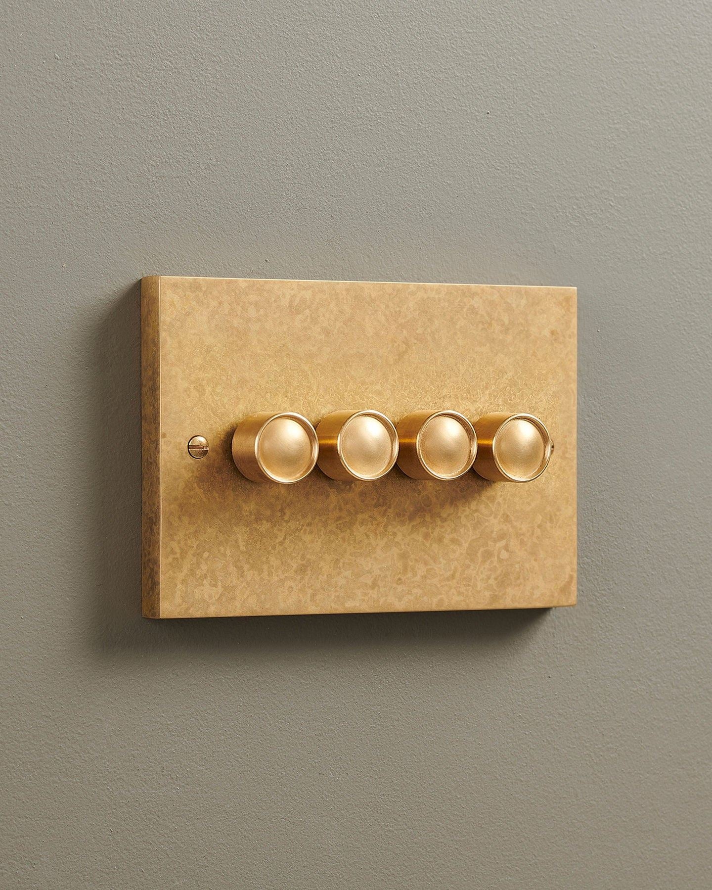 An oblique view of a 4 gang box dimmer switch in a mottled aged brass finish.