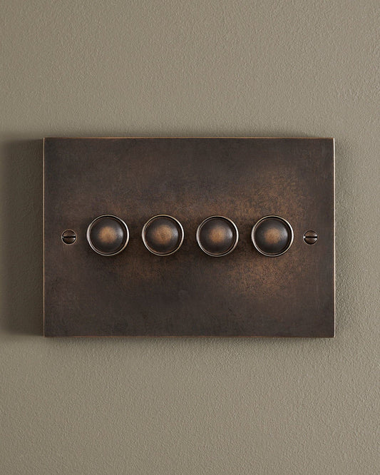 A straight-on view of a 4 gang box dimmer switch in a dark oxidised brass finish.