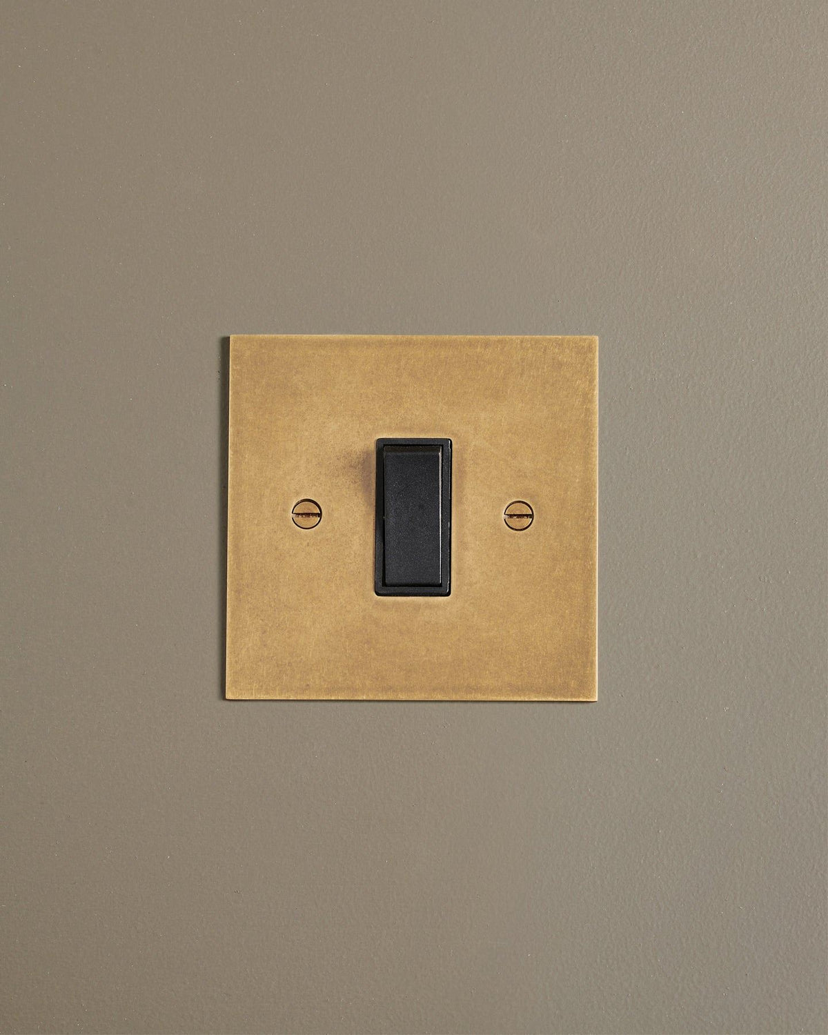 A straight-on view of a classic 20 amp switch in a mottled aged brass finish. TEST
