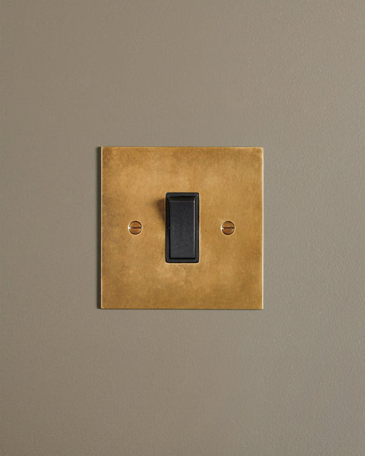 A straight-on view of a classic 20 amp switch in a warm burnished brass finish.