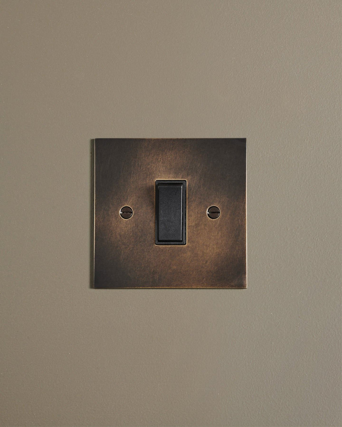 A straight-on view of a classic 20 amp switch in a dark oxidised brass finish. TEST