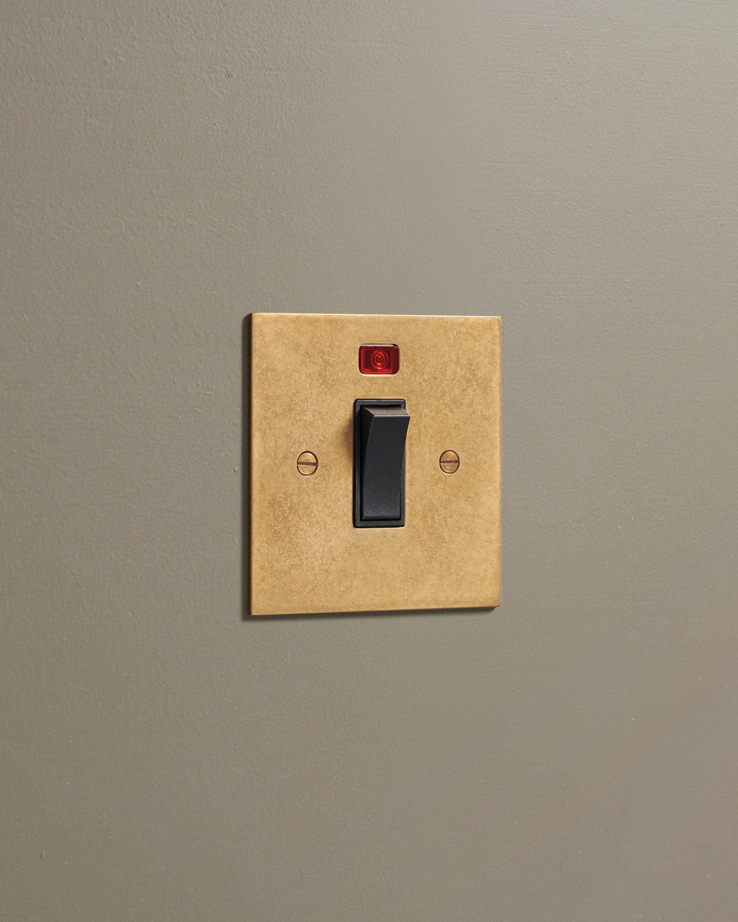 An oblique view of a classic 32 amp cooker switch in a mottled aged brass finish.