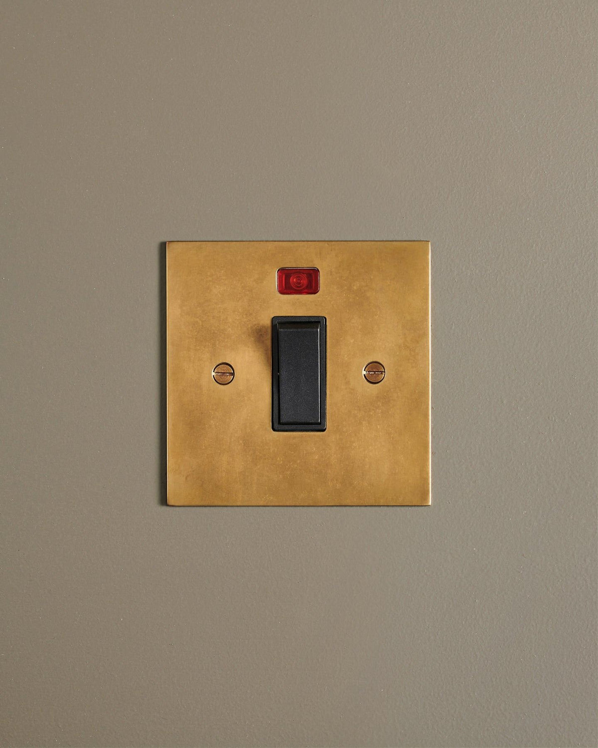 A straight-on view of a classic 32 amp cooker switch in a warm burnished brass finish. TEST