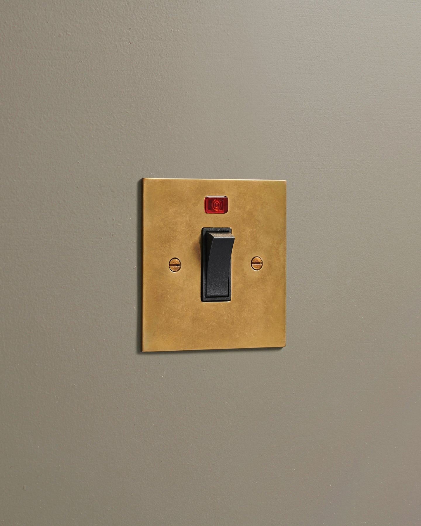 An oblique view of a classic 32 amp cooker switch in a warm burnished brass finish.