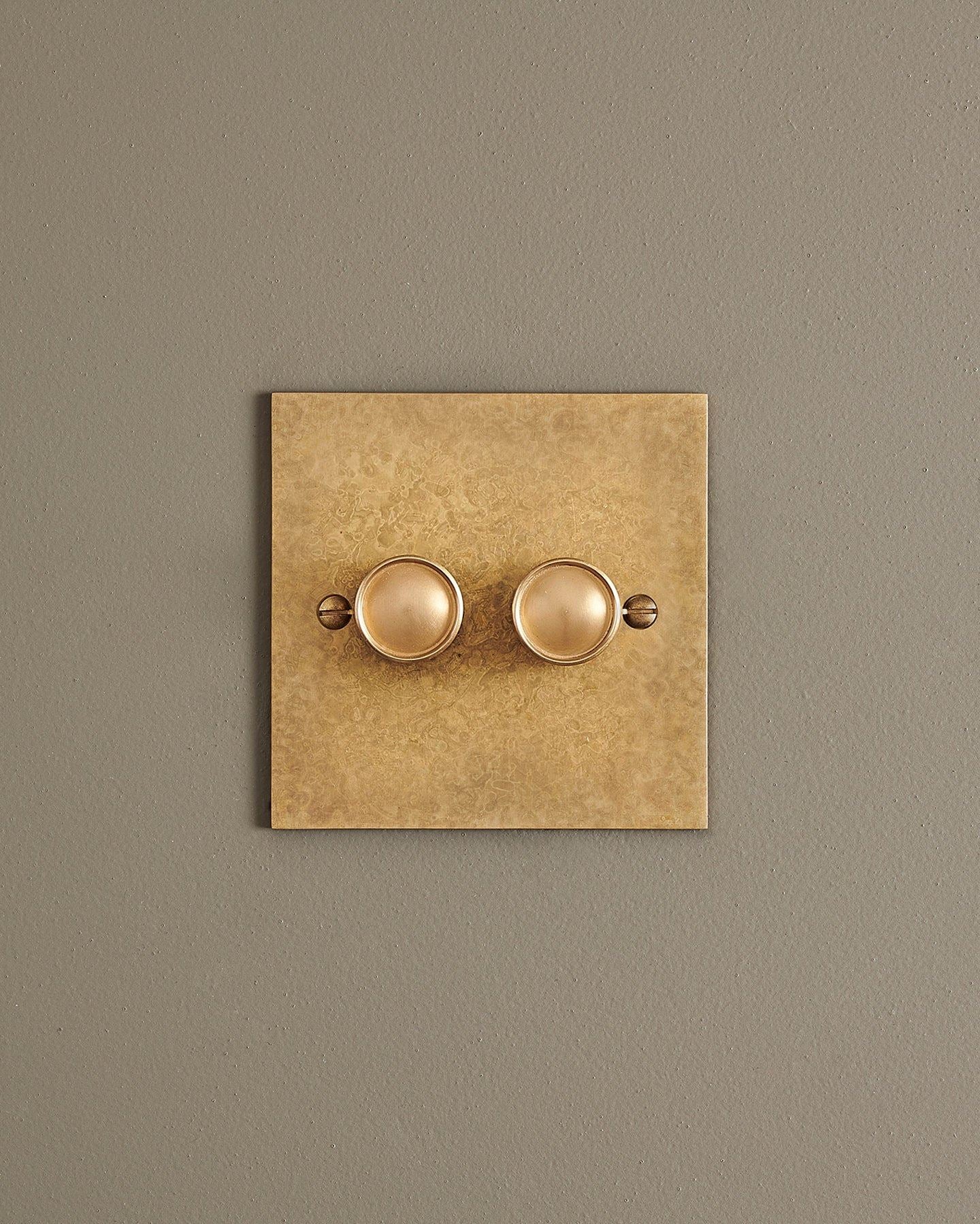 A straight-on view of a 2 gang classic dimmer switch in a mottled aged brass finish.