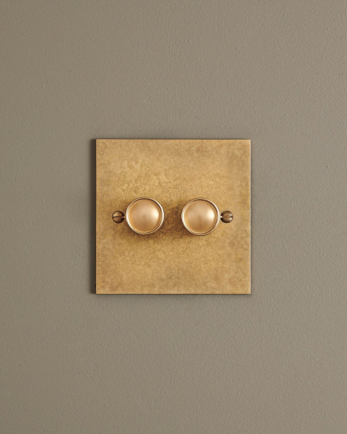 A straight-on view of a 2 gang classic dimmer switch in a mottled aged brass finish. TEST