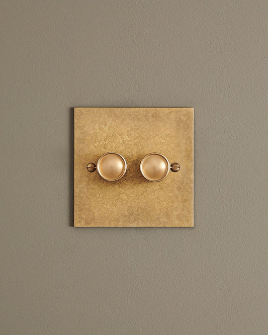 A straight-on view of a 2 gang classic dimmer switch in a mottled aged brass finish.