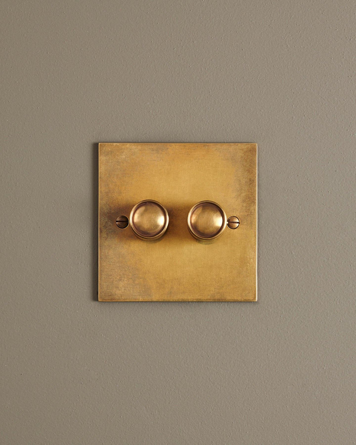 A straight-on view of a 2 gang classic dimmer switch in a warm burnished brass finish. TEST