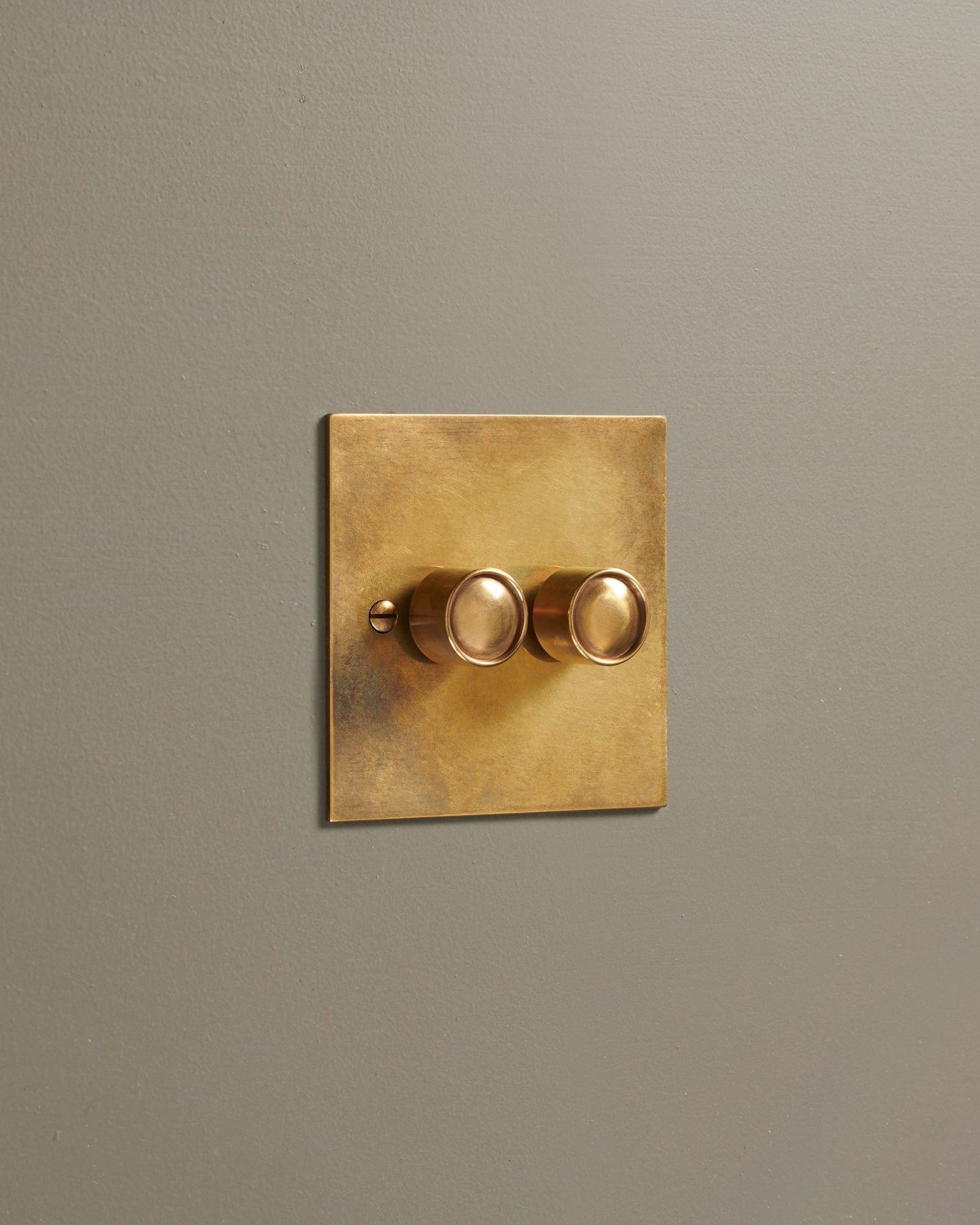 An oblique view of a 2 gang classic dimmer switch in a warm burnished brass finish.