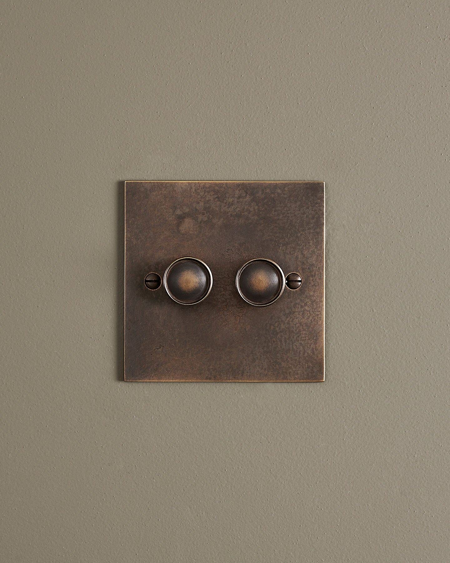 A straight-on view of a 2 gang classic dimmer switch in a dark oxidised brass finish.