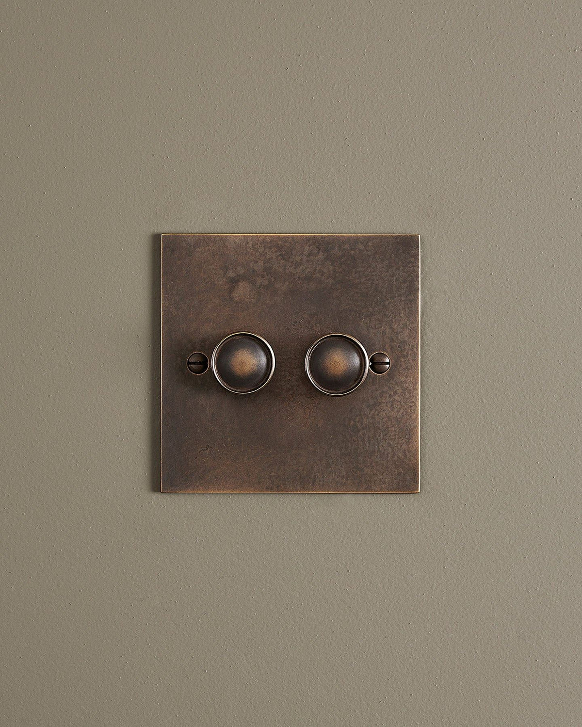 A straight-on view of a 2 gang classic dimmer switch in a dark oxidised brass finish. TEST