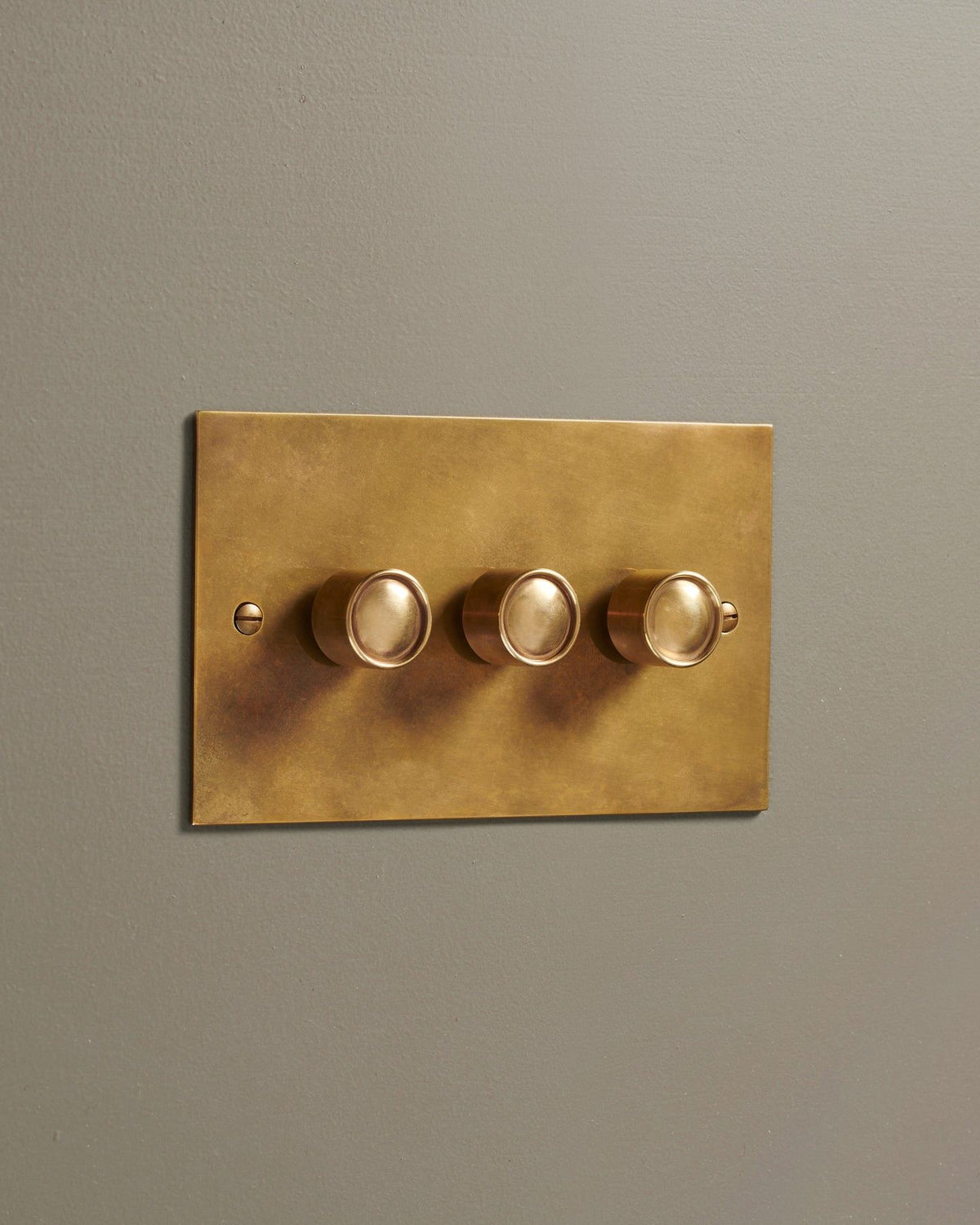 An oblique view of a 3 gang classic dimmer switch in a warm burnished brass finish. TEST