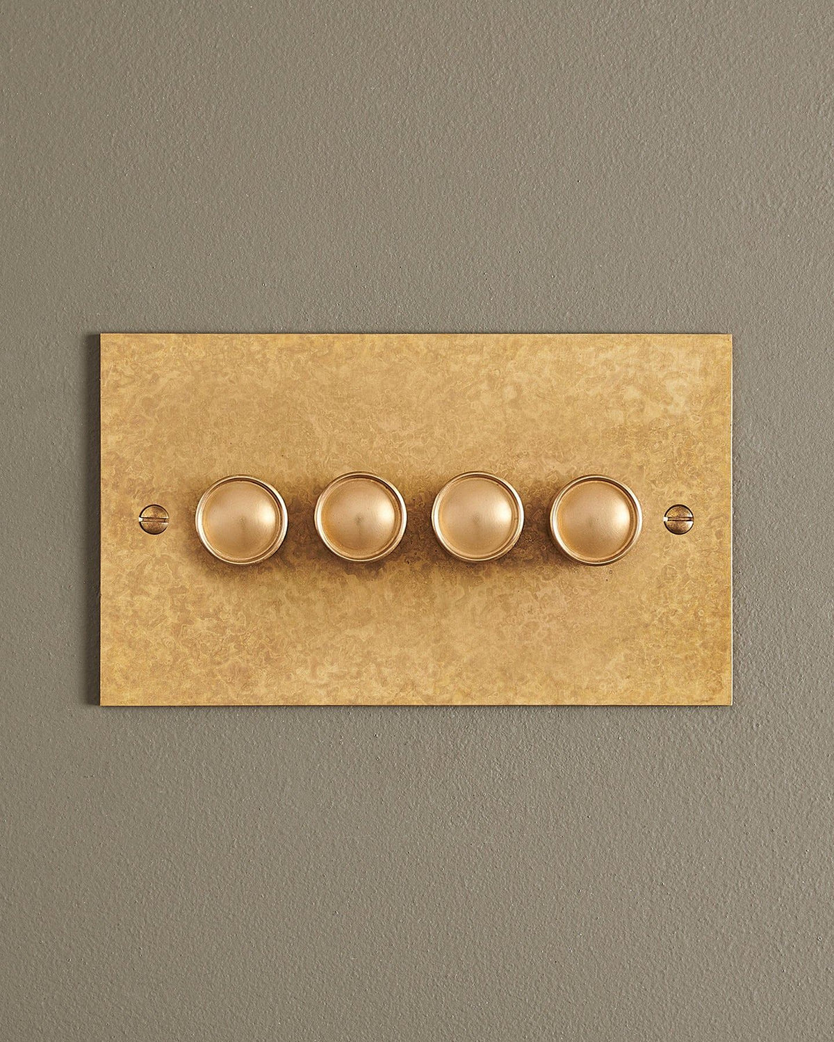 A straight-on view of a 4 gang classic dimmer switch in a mottled aged brass finish. TEST